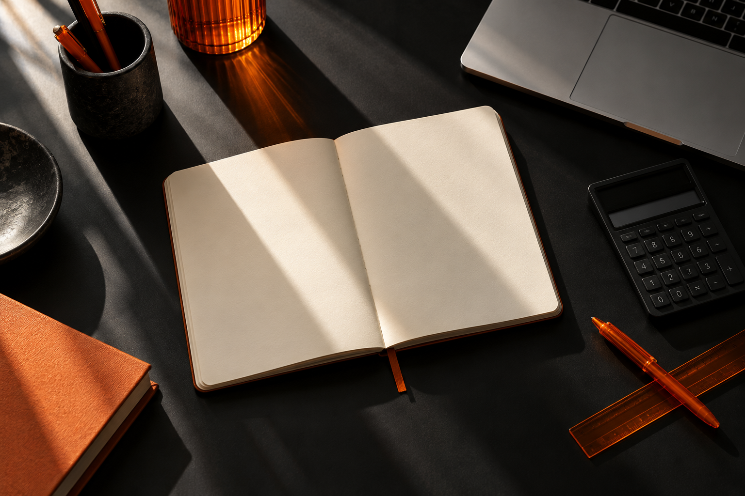 Notebook, calculator and laptop on a sunlit creative workspace